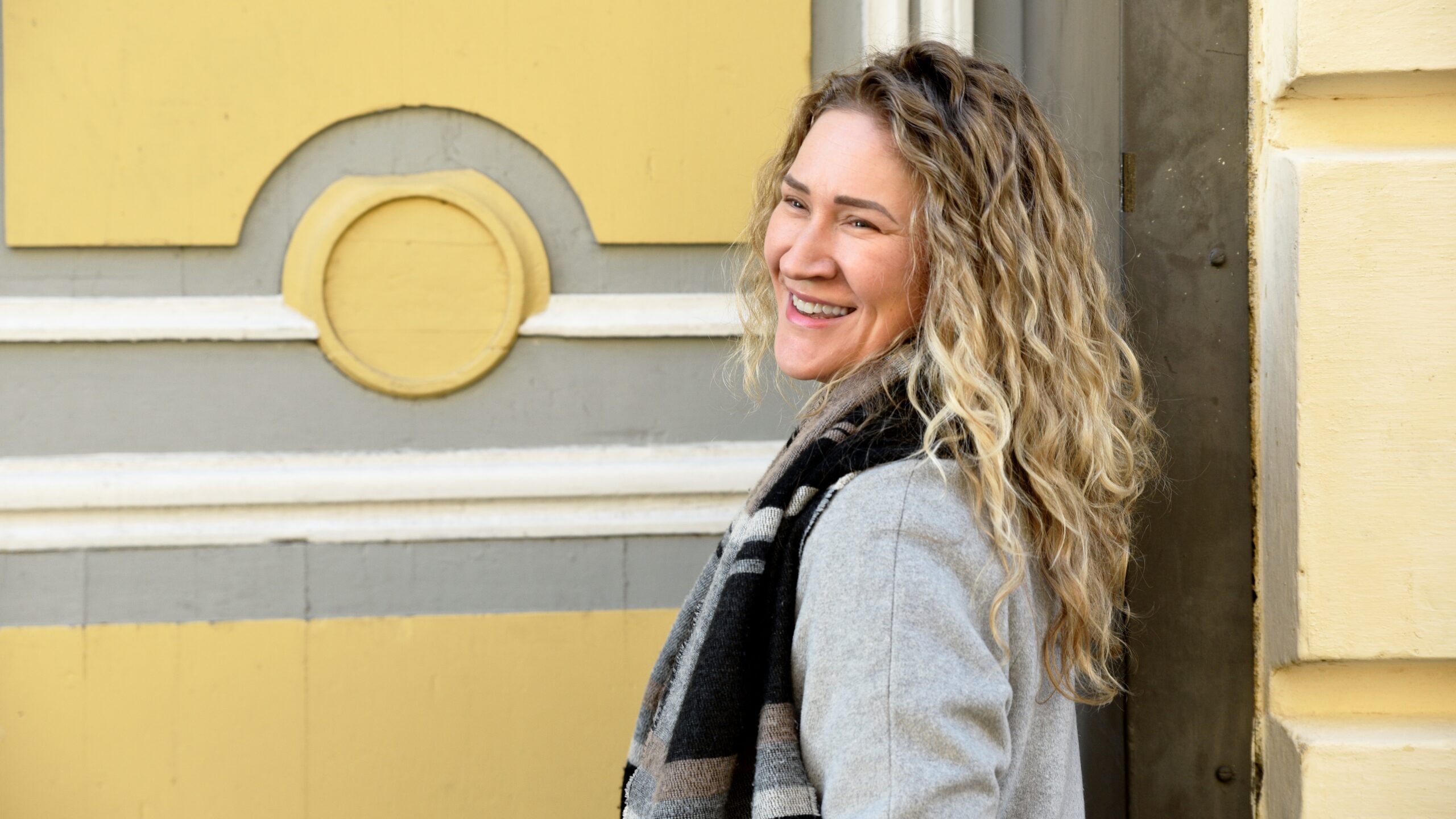 Kaupungilla nuori nainen katsoo alas kohti puhelintaan, jonka näyttö näkyy vilaukselta.