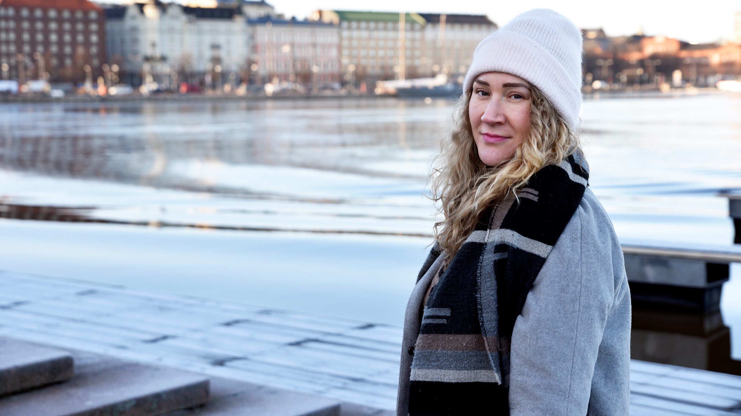 Naiset seisovat hymyillen yhdessä sateenvarjon alla.